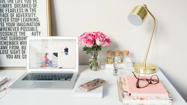 Bright workspace with a laptop, lamp and notebooks