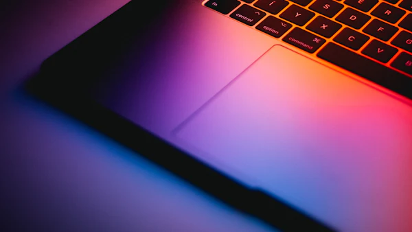 Close-up of a MacBook Pro keyboard lit by a colourful screen