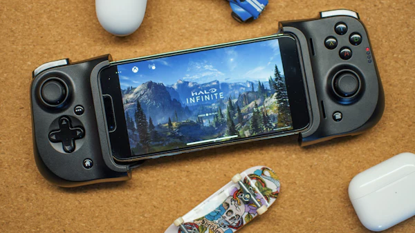 Android phone in a mobile game controller running an open-world game, next to a gamepad